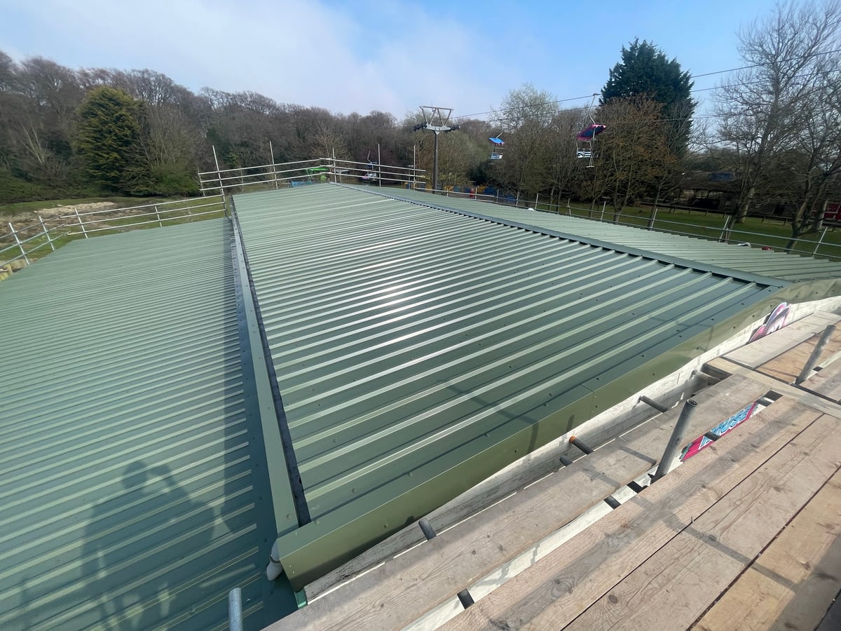 A green standing-seam metal roof fitted by District Roofing