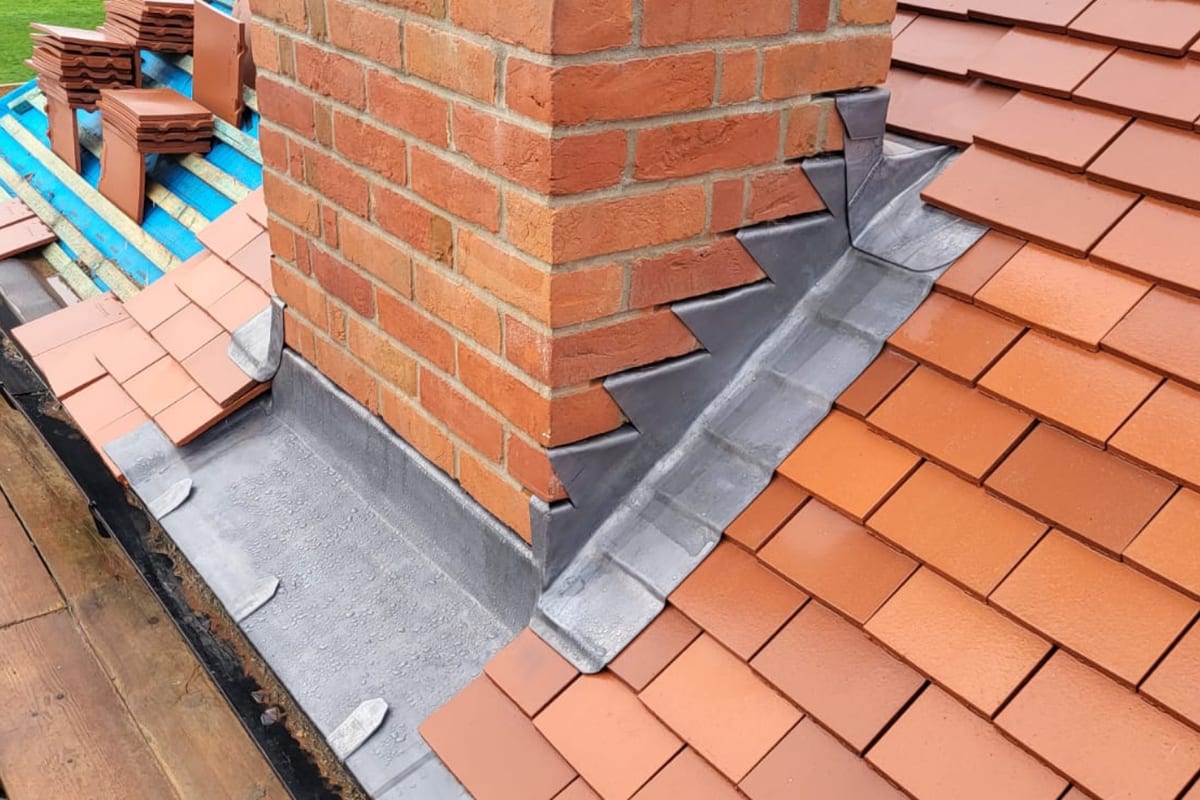 A brick chimney with new lead flashings and clay tiles