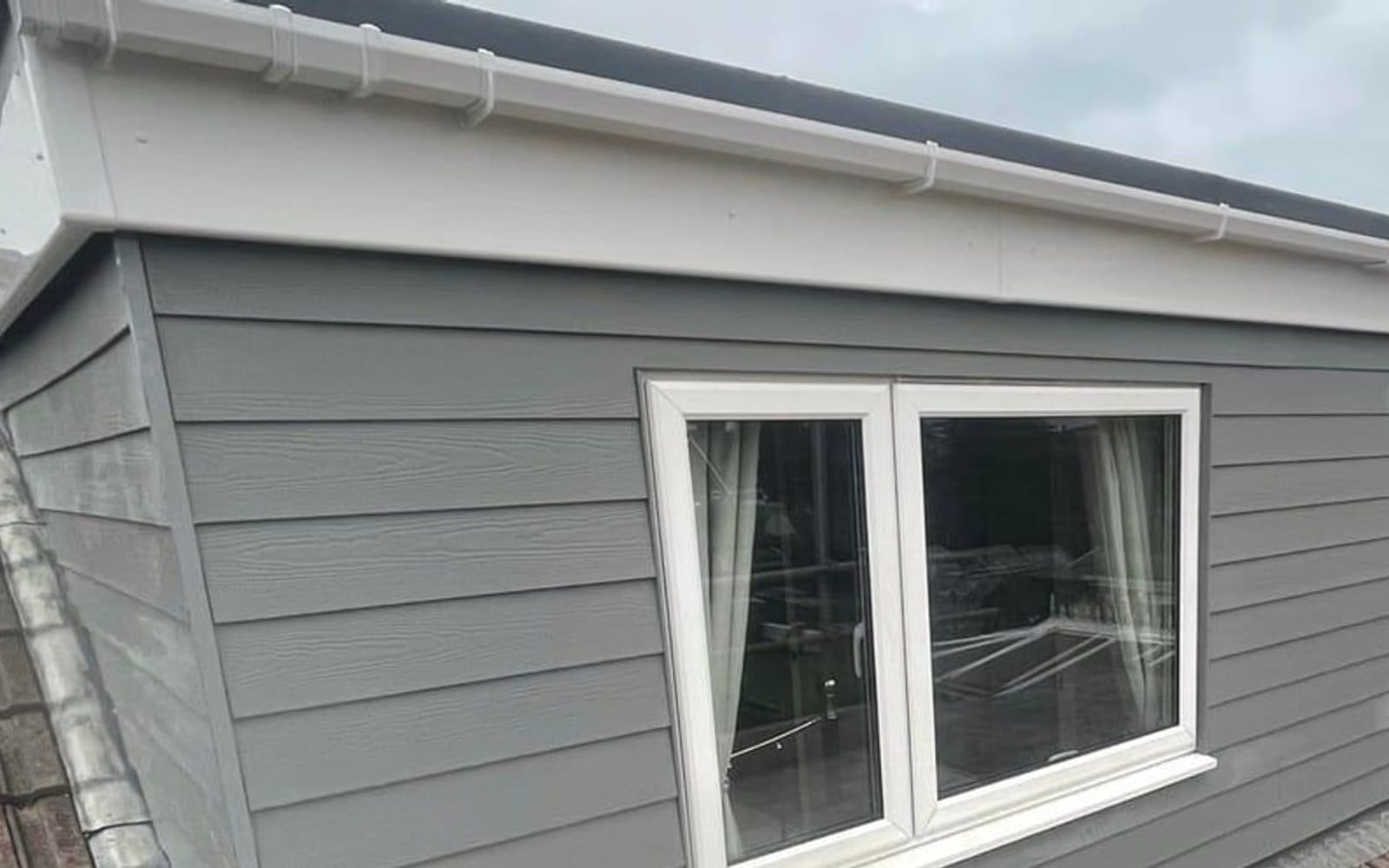 Grey cladding fitted to a house side by District Roofing