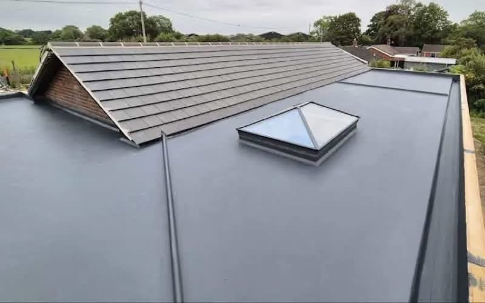 A new flat roof with a glass roof lantern, beside a tiled pitched roof