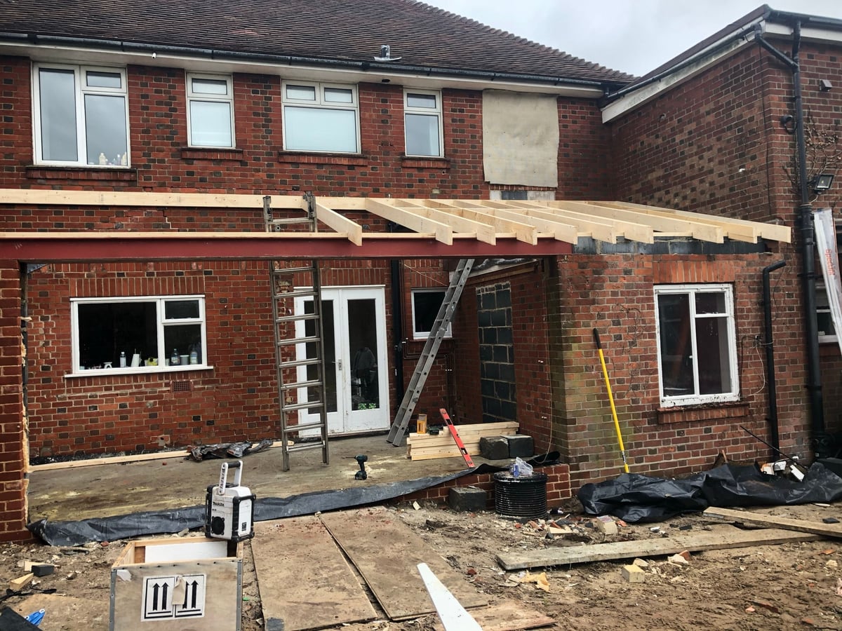 A glass conservatory before, and the new roof structure being built