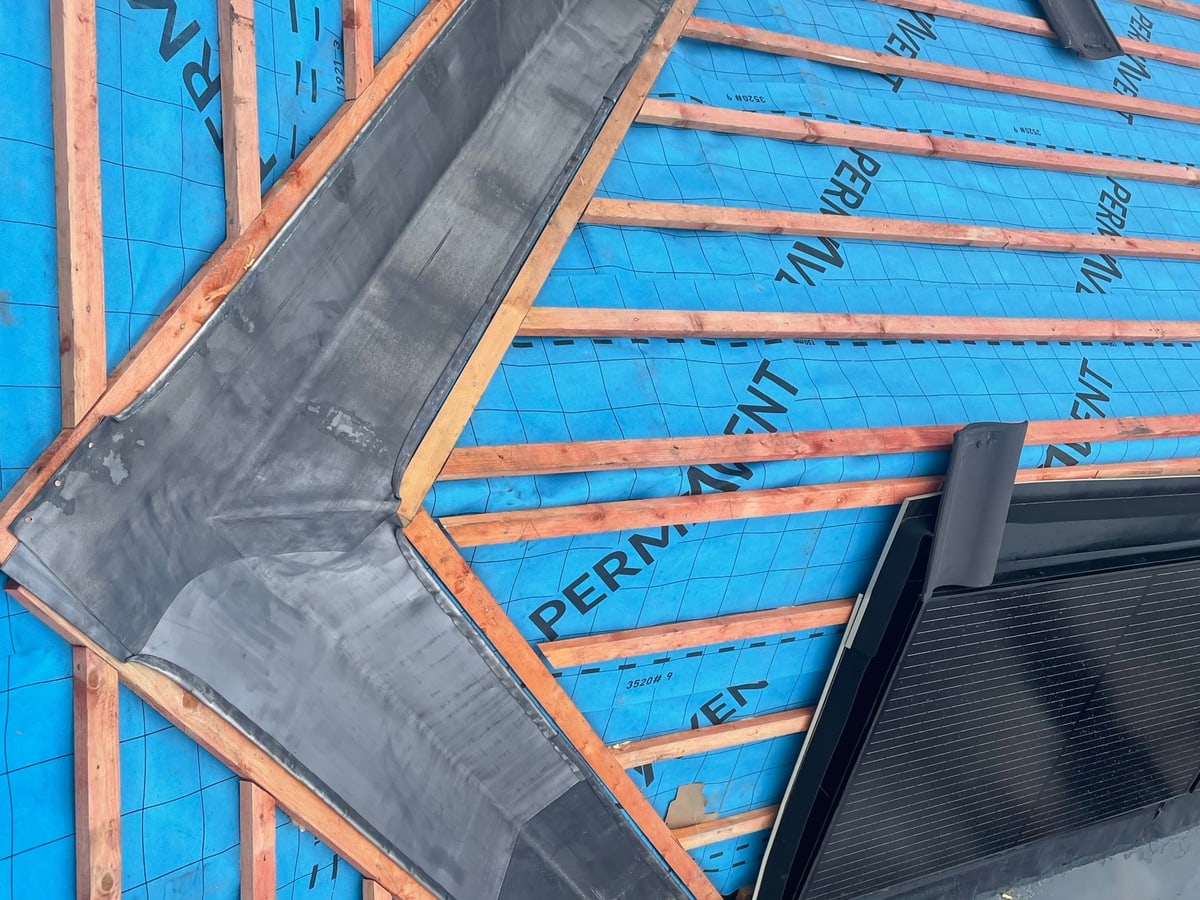 Concrete roof tiles being laid over new membrane and battens